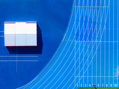 Aerial view of the blue running track of Stadion Podskarbinska with white lane markings and a small white building Warszawa, Mazowieckie, Poland.