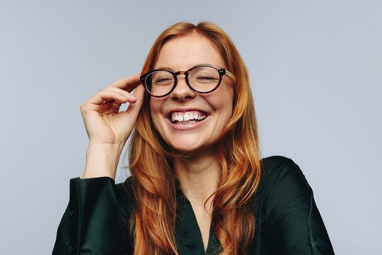 Woman adjusting glasses while laughing in studio