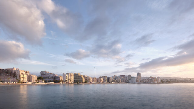 Morning panorama of Calpe seafront skyline over calm Mediterranean water, a peaceful coastal travel destination on the Costa Blanca in Spain
