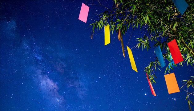 七夕の短冊と天の川が輝く夜空の背景素材　笹の葉とカラフルな短冊が揺れる夏の風物詩　文字入れ用の広いコピースペースがある夜景の壁紙　願い事や行事案内チラシに活用できる幻想的な夏の夜のデザイン用写真
