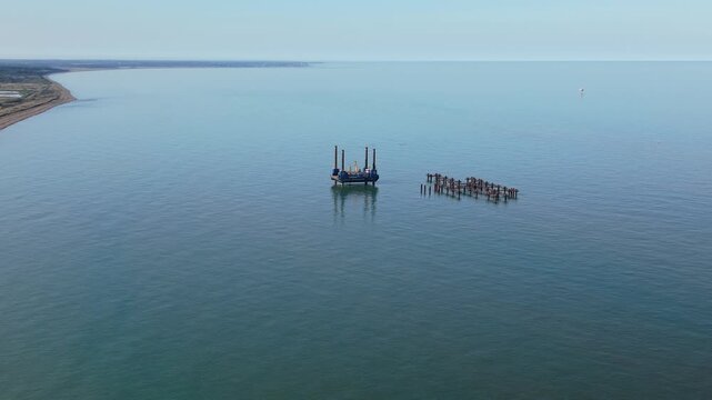 Aerial view of jackup barge and offshore construction pilings near Suffolk coastline