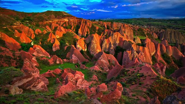 A high-angle panoramic shot of the iconic Red Valley in Cappadocia, Turkey, during a dramatic golden hour. Intense sunset light illuminates the vibrant orange and red volcanic tuff rock formations .