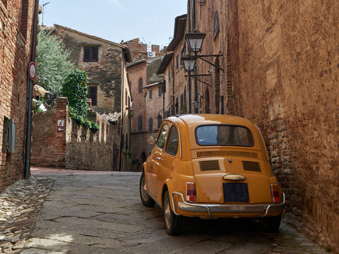 Classic vintage car parked in a narrow historic street of the ancient town Certaldo in Tuscany Italy