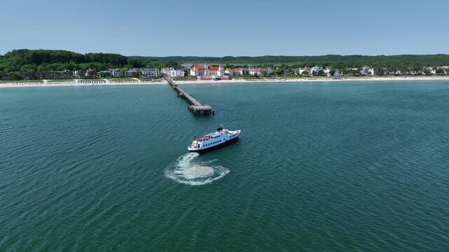 Aerial footage of passenger ferry approaching seaside pier of Binz the seaside resort on Baltic coast on island of R&uuml;gen, Germany.