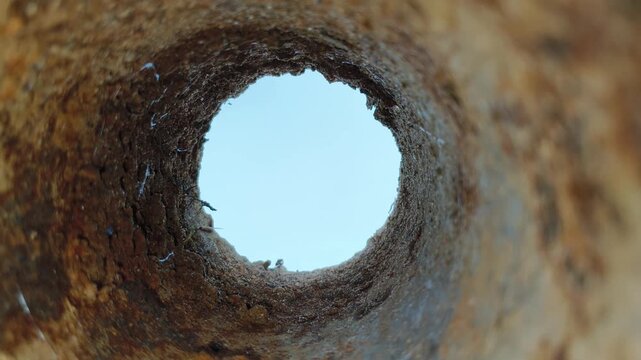 Close-up deep endless round long rusting iron metal pipe hole with oxidation or corrosion decay damage inside. Old abandoned bore well, sewer pipeline or drainage tube bad condition concept.