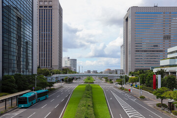 ビジネス街の高層ビル群に囲まれた広い幹線道路と中央分離帯の緑 © 茂明 北村