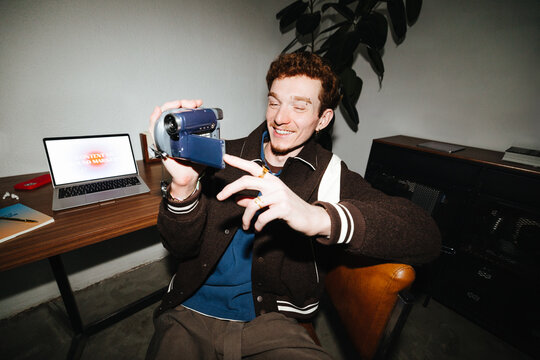 Man recording video with camcorder at laptop for vlogging and content creation