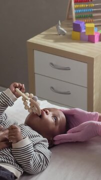 Vertical video of African American baby lying on examination table while pediatrician in medical gloves examining head. Footage is ideal for pediatric healthcare marketing