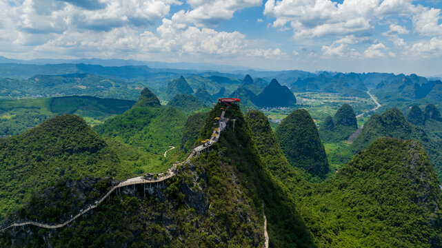 Aerial view of the Ruyi Peak ropeway scenic area featuring a mountain ridge walkway and observation deck among karst peaks in Yangshuo, Guangxi, China.