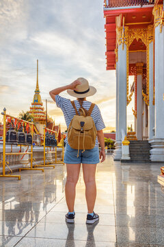 Female tourist in hat with backpack at a Buddhist temple