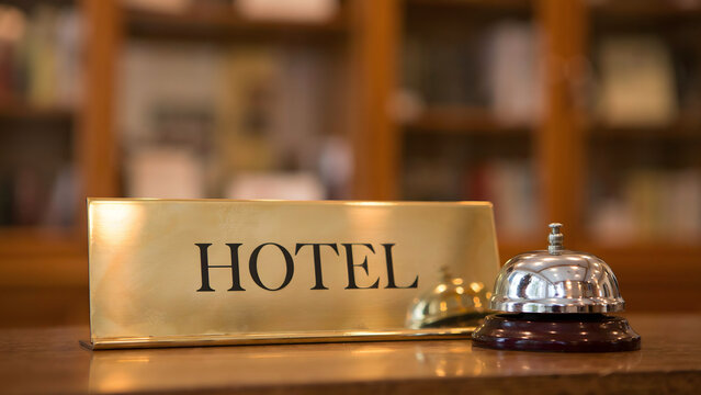 A gold sign with the word hotel and a metal service bell on a counter