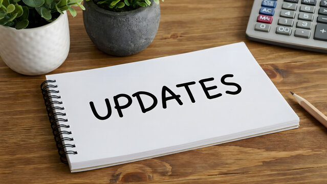 A spiral bound notebook with the word updates written on a wooden desk