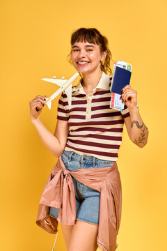 Young woman excited for summer travels with tickets and airplane model in hand