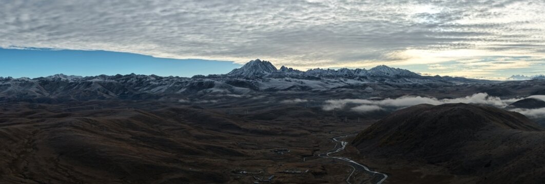 Sunrise aerial panorama of Yala Snow Mountain beneath a dramatic cloud deck, Sichuan, China