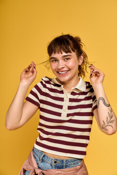 Playful young woman enjoying summer vibes with a vibrant yellow backdrop and stylish attire