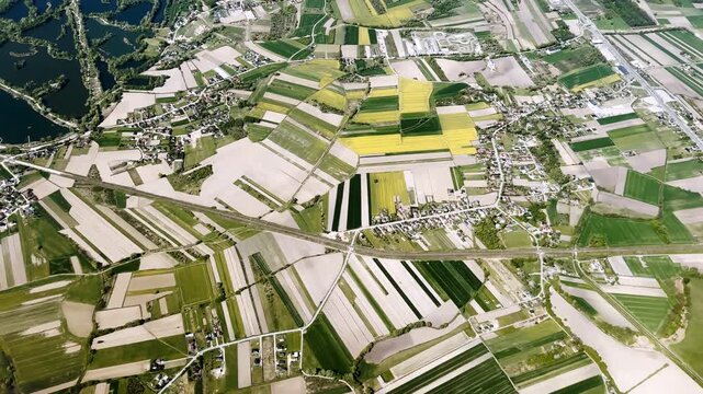 Aerial view of patchwork farmland, villages, roads and a dark lake near Krakow, Poland, showing rural landscape patterns from high altitude.