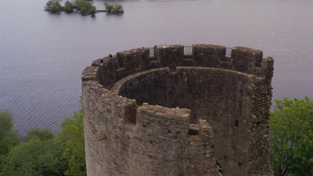 Sweeping aerial orbit ascending with tilt down revealing detailed tower top of Cloughoughter Castle, Lough Oughter. Ireland