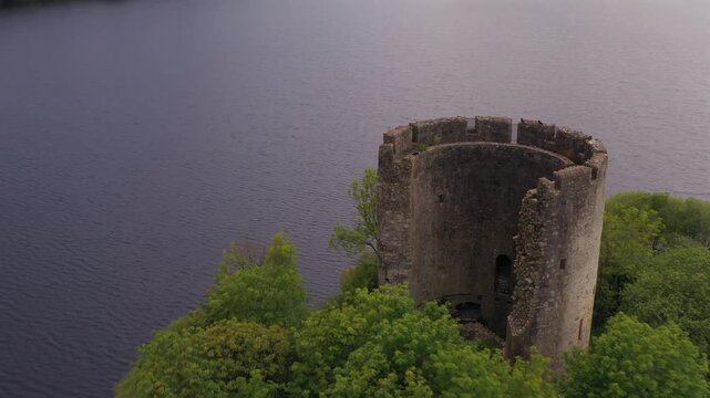 Aerial pullback and orbit of Cloughoughter Castle revealing interior through broken circular tower wall, County Cavan Ireland
