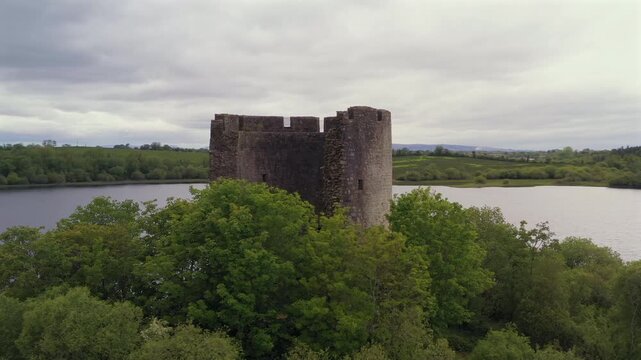 Aerial orbit of famous Cloughoughter Castle on island surrounded by trees. Lough Oughter County Cavan Ireland