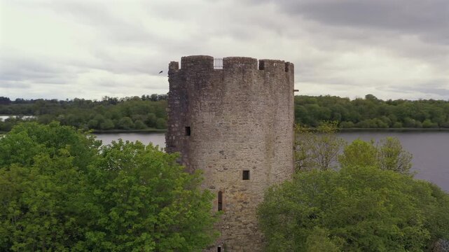 Aerial orbit of Cloughoughter Castle showcasing picturesque circular tower construction details and stonework, County Cavan