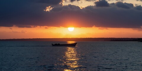 Fototapeta premium Small boat moves on calm sea water during golden sunset. Dark clouds gather above orange horizon line. Peaceful evening journey over ocean surface.