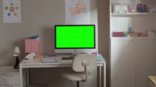No people interior shot of pediatrician office desk displaying computer monitor with green screen chroma key and stethoscope on workspace. Perfect for medical software ads or pediatric clinic promos