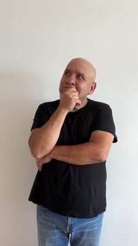 Hombre latino de 50 a&ntilde;os pensativo agarr&aacute;ndose la barbilla