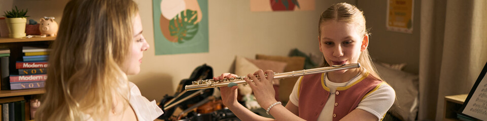 Teenage girls studying music and playing flute with violin during lesson at home, supporting arts education and creative skill development. Useful for music school, tutoring, youth learning © DragonImages