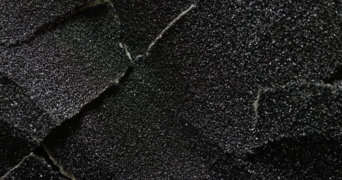 Dark cracked texture slow rotation. Close-up of deep black surface with intricate white vein patterns and natural cracks. Smooth continuous rotation reveals evolving light reflections.