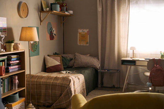 Wide angle view of child bedroom featuring study desk, backpack, books, bed, and school supplies, presenting home learning routine and back to school marketing use