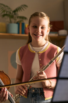 Portrait of Caucasian girl studying music and holding flute during lesson with violin player, learning performance skills. Useful for music school, arts education, youth training marketing