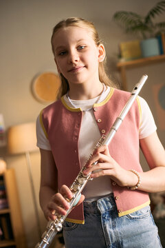 Portrait of Caucasian girl holding flute and studying music, practicing instrument skills for creative education and youth development. Ideal for music school promotion or lesson ads, vertical