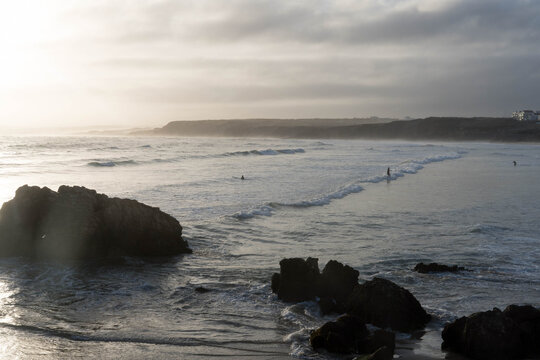Surfers catching waves in the early morning light. Baleal, Peniche, Portugal