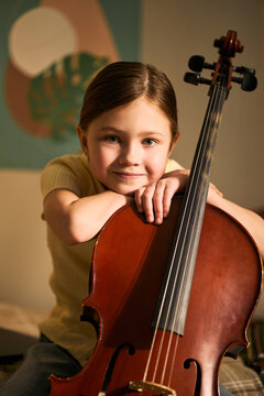 Portrait of Caucasian girl studying music and holding cello, showing childhood learning and creative development. Ideal for music school promotion, arts education marketing, vertical
