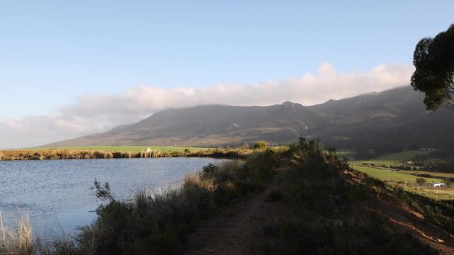 pond , grass , trees and Klein Mountains, Stanford, South Africa as the morning fog burns off
