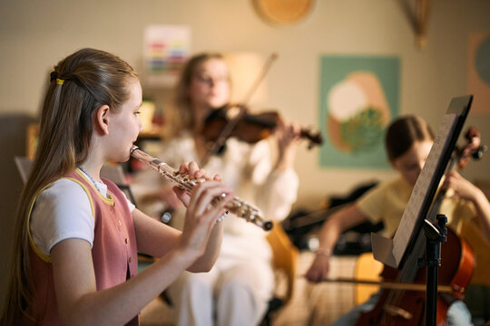 Kids studying music and playing flute, violin, and cello during lesson, developing creativity and teamwork. Ideal for music education, arts programs, youth learning marketing