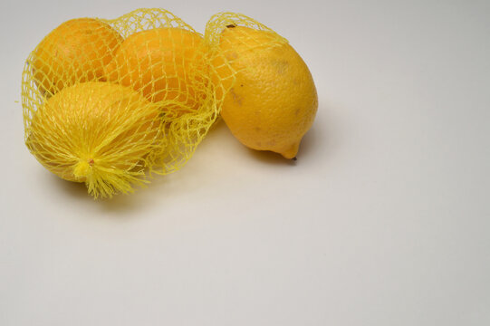 yellow lemon in a yellow mesh  on a white background corner composition horizontal layout, lemons close up with generous copy space,