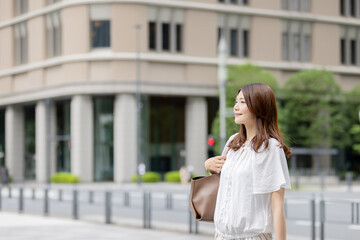 Fototapeta premium オフィス街を歩く笑顔の日本人女性