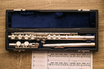 Close up of flute resting in case above sheet music, supporting music education, instrument practice, classical training concepts. Ideal for school, lesson, recital, learning ads © DragonImages