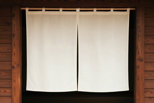Traditional Japanese noren curtain hangs on a wooden door frame. The simple white fabric divides an entrance, suggesting a shop or restaurant interior. It creates a warm, authentic atmosphere.