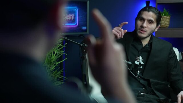 Podcast host speaking into microphone in modern blue lit studio, arguing with pointed fingers disagreeing in animated discussion