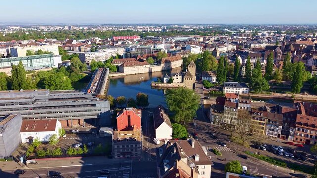 Hotel d'Alsace building next to river with historic Ponts Couverts bridges and defensive towers in background in Strasbourg, France. Aerial forward, cityscape