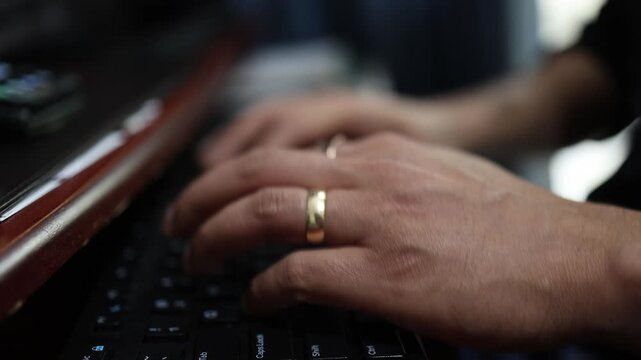 Detailed view of hands typing on a keyboard in a low-light setting. The composition captures the texture and focus of the fingers in motion, highlighting the dynamic energy of digital work.