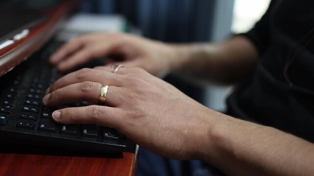 Detailed close-up shot of hands typing on a keyboard in an office environment. Warm lighting evokes productivity, emphasizing the focus on task execution. Captures office work essence.