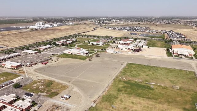Drone push in showing the campus of West Hills College in Lemoore. California. With its academic buildings. Parking lots. And sports fields surrounded by the rural landscape of the Central Valley