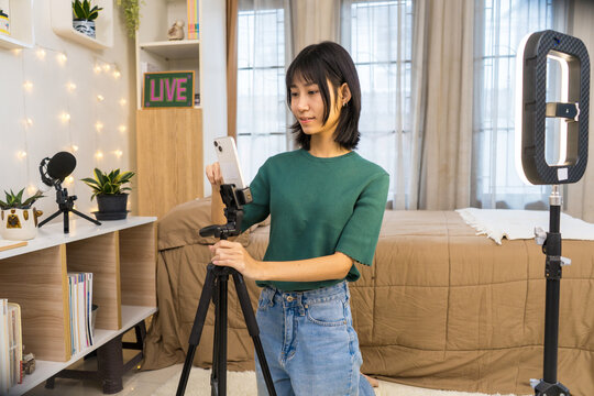 Young Content woman Setting Up Smartphone for Live Streaming, Vlogger Creating Social Media Content in Bedroom Studio