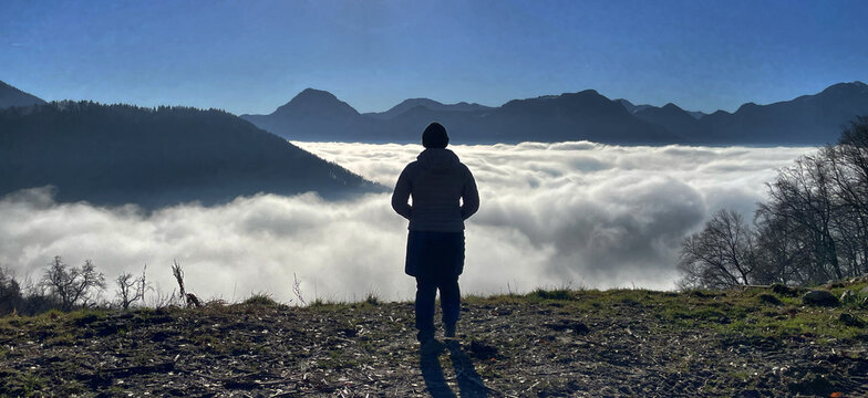 Frau (Wanderer) von hinten blickt von oben auf ein Wolkenmeer, Samerberg, Alpen, Bayern, Deutschland