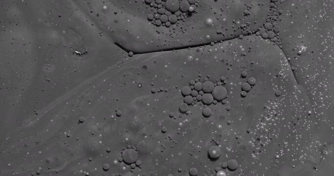Black bubbly liquid. Close-up of dark viscous surface with foam and bubbles. 