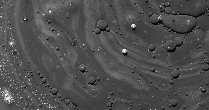 Black bubbly liquid slow. Close-up of dark viscous surface with foam and bubbles. 