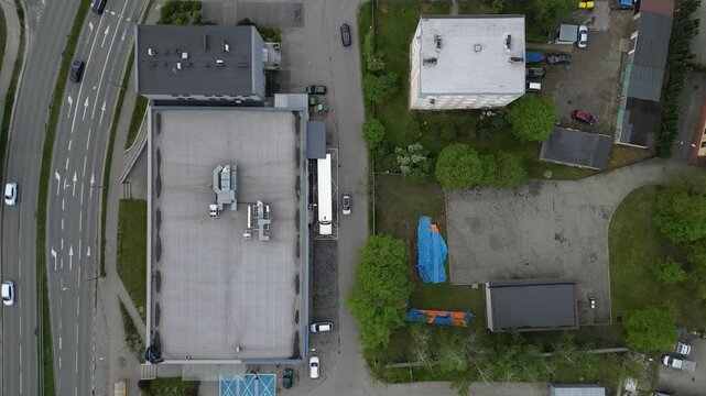 Aerial top down view of urban street traffic and commercial building rooftop with HVAC ventilation system.